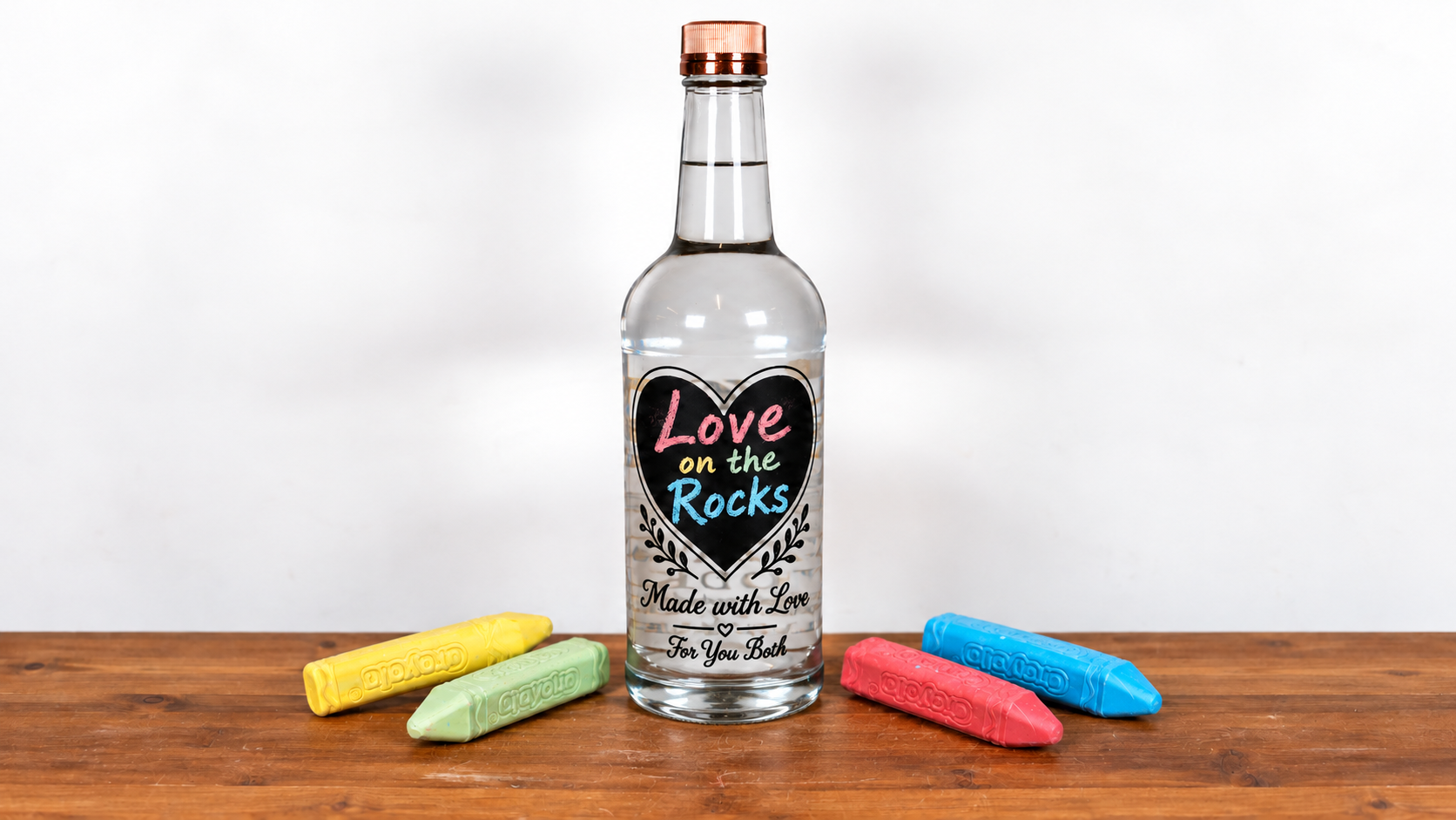 Engraved Tito’s vodka bottle with a heart painted in chalkboard paint reading “Love on the Rocks,” surrounded by colorful chalk.