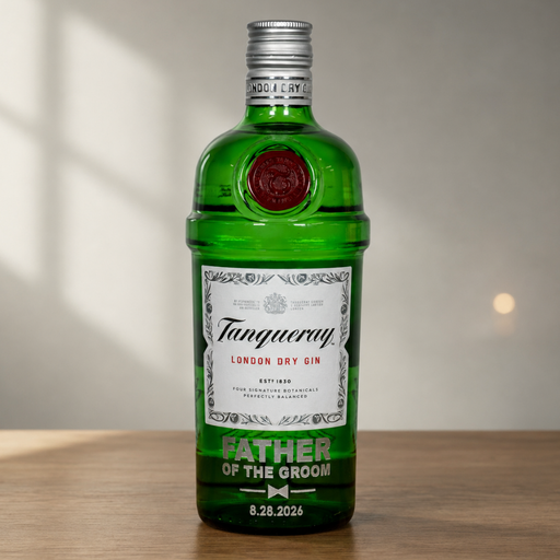 A green glass bottle of Tanqueray London Dry Gin with a custom printed label reading 'FATHER OF THE GROOM' and a date, standing on a wooden surface against a softly lit neutral background.