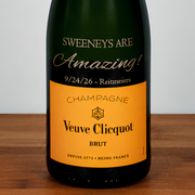 A bottle of Veuve Clicquot Brut champagne with a custom printed label that reads 'SWEENEYS ARE Amazing! 9/24/26 - Reitmeiers' in gold lettering on a dark green bottle with a bright orange label.