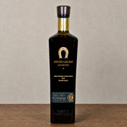 A bottle of Herradura Legend tequila standing upright on a wooden surface against a neutral gray background.