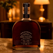 A bottle of Phil Collins Special Reserve whiskey with a custom 'Happy 40th Birthday' birthday engraving, displayed on a marble surface with a warm, blurred background.