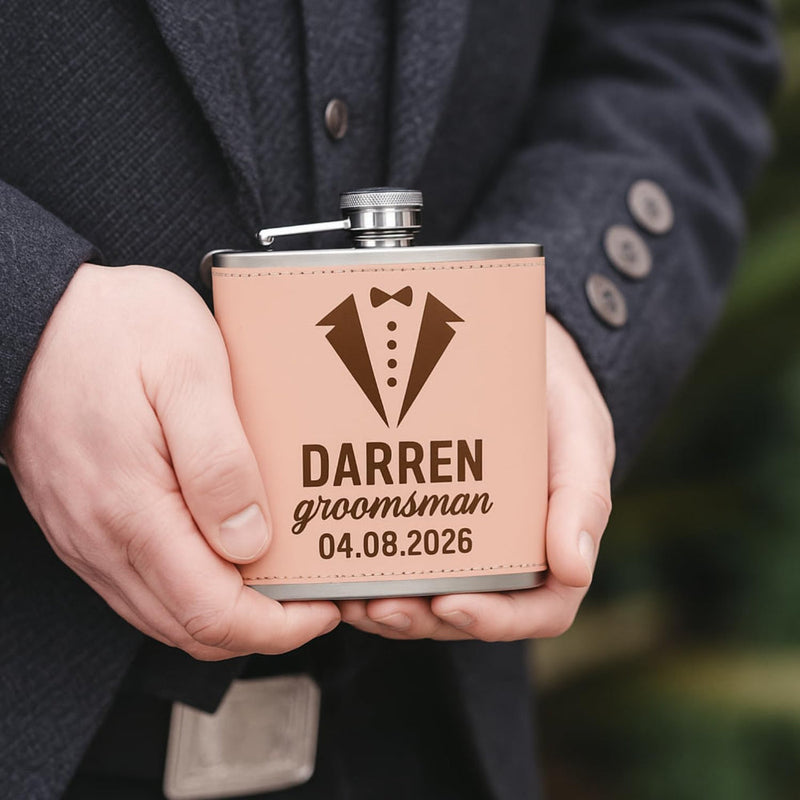 Person holding a personalized flask with a tuxedo design and engraved text.