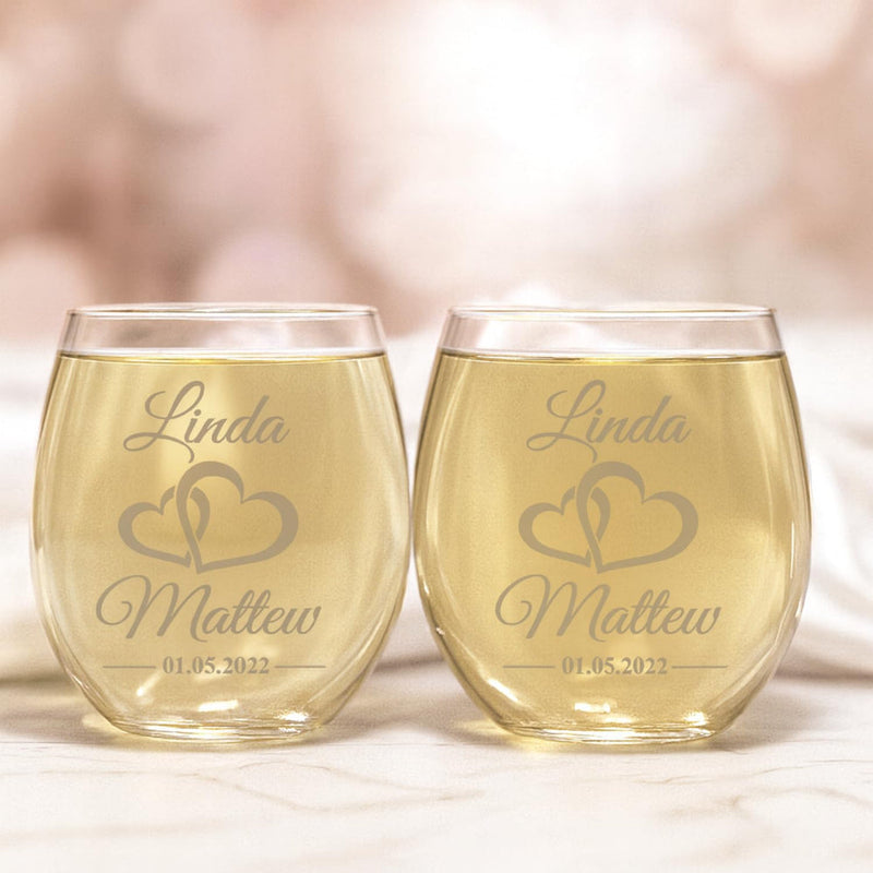 Two personalized wine glasses with engraved names and date on a soft background