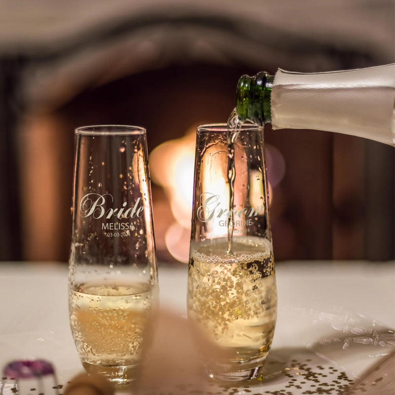 Champagne being poured into personalized 'Bride' and 'Groom' glasses with a blurred background.