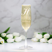Champagne flute with engraved text and white tulips on a light background