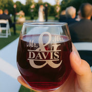 Stemless wine glass with 'Mr. & Mrs. Davis' engraving held by a hand outdoors.