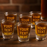 Set of shot glasses with 'YOUR TEXT HERE' text on a wooden surface.