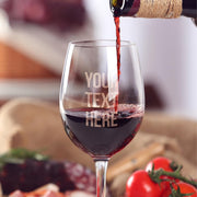 Wine glass with 'Your Text Here' text being filled with red wine, surrounded by fruits and bread.