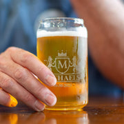 Glass of beer with a brand logo held by a hand on a wooden surface