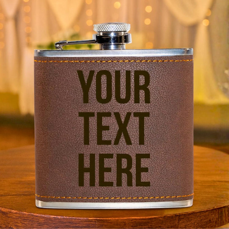 Brown leather flask with 'YOUR TEXT HERE' text on a wooden surface.