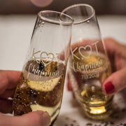 Two personalized champagne flutes held by hands with a blurred background