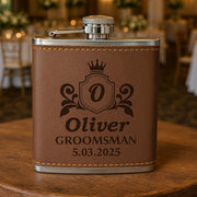 Brown leather flask with engraved text on a wooden surface, blurred background of a wedding reception.