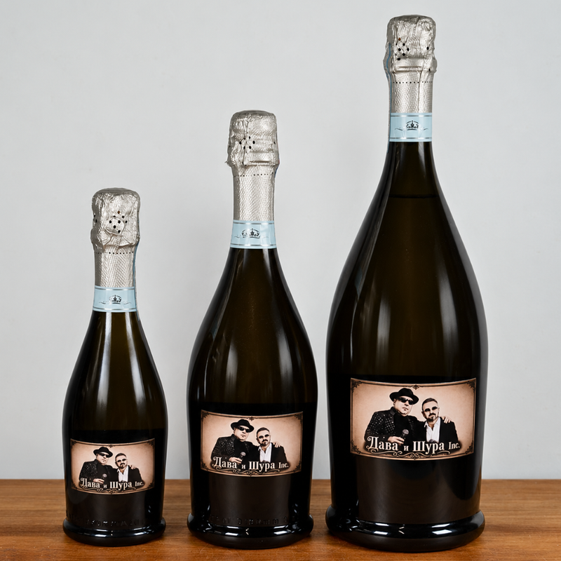 Three dark glass champagne bottles of different sizes arranged by height on a wooden surface against a light gray background. Each bottle has a custom vintage-style label featuring a black-and-white portrait of a man and woman with the text 'Mama & Sypia'.