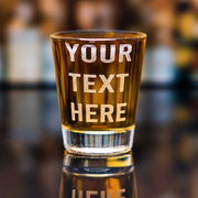 Personalized engraved whiskey shot glass with custom text, amber glass, bar setting